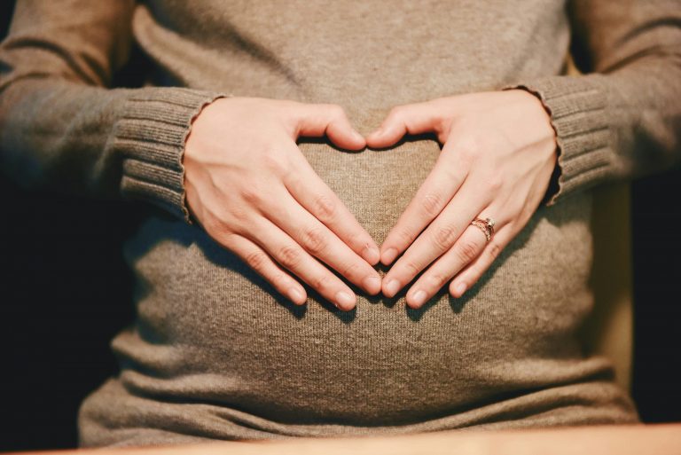 Unas manos forman un corazón sobre una barriga de embarazada