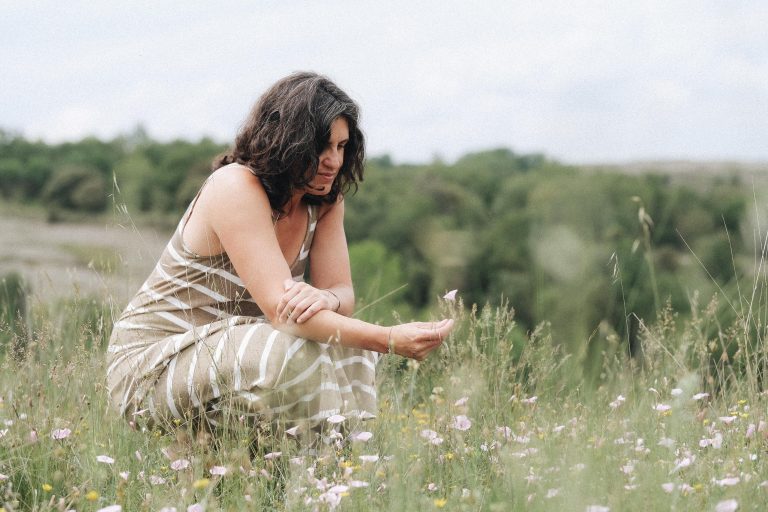 Laia Balmes agachada en un prado de flores silvestres, acariciando una flor