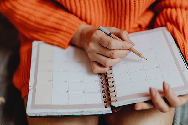 Unas manos escribiendo en una agenda de planificación mensual
